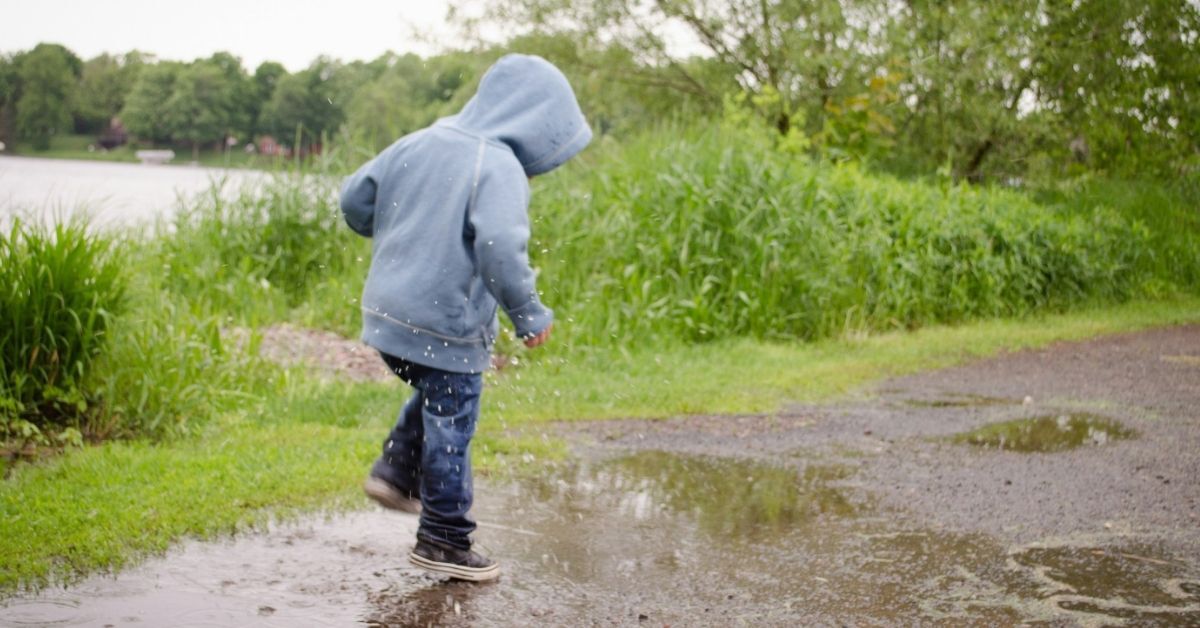 Kind dat speelt in de regen